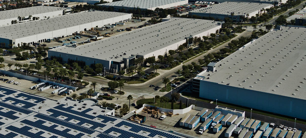 An aerials shows a warehouse in Santa Fe Springs CA with a solar array. The potential for additional solar is seen in the background.